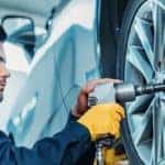 mechanic using pneumatic socket driver to remove tires