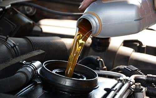 A service technician pouring new engine oil.