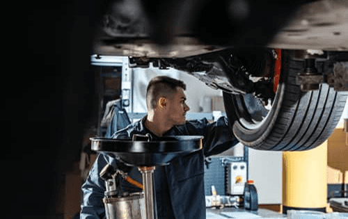 Service technician draining vehicle fluids.