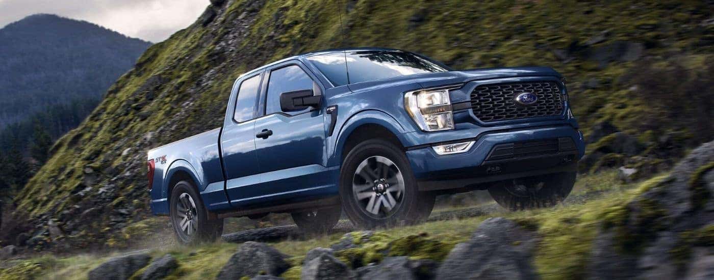 Blue 2023 Ford F-150 STX driving off-road
