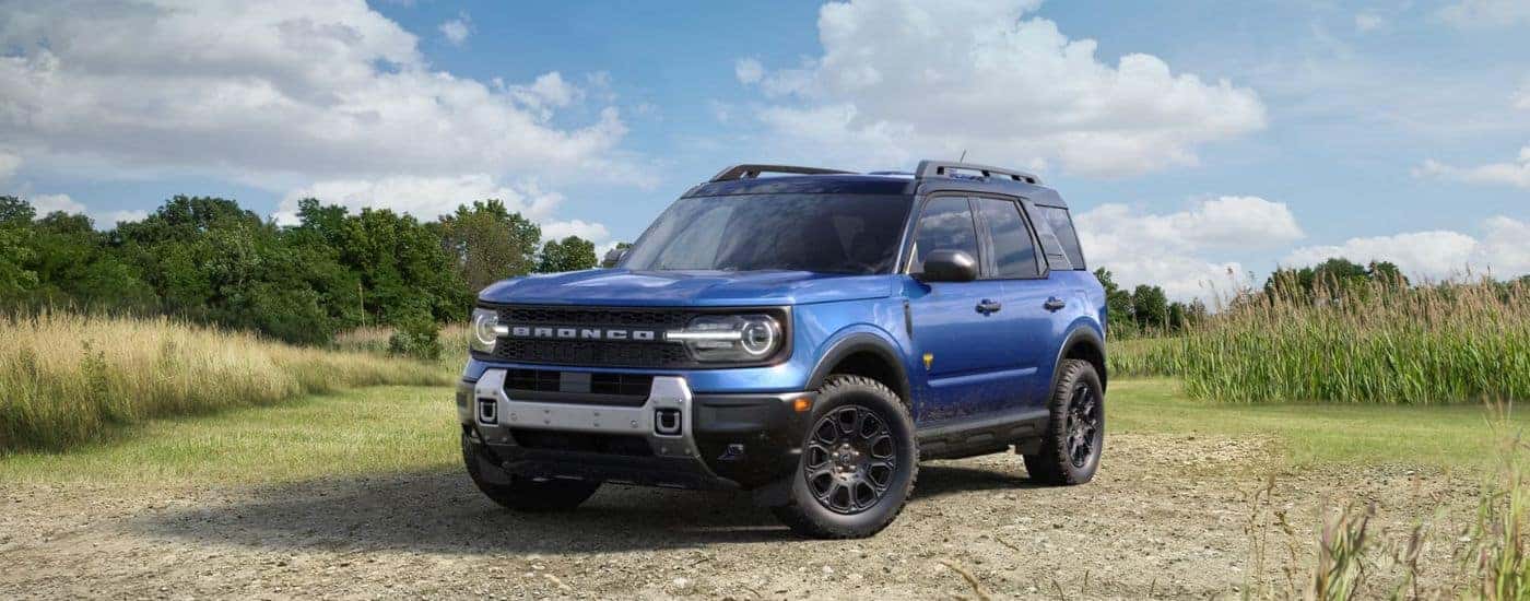 A blue 2026 Ford Bronco Sport parked on a dirt and grass field.