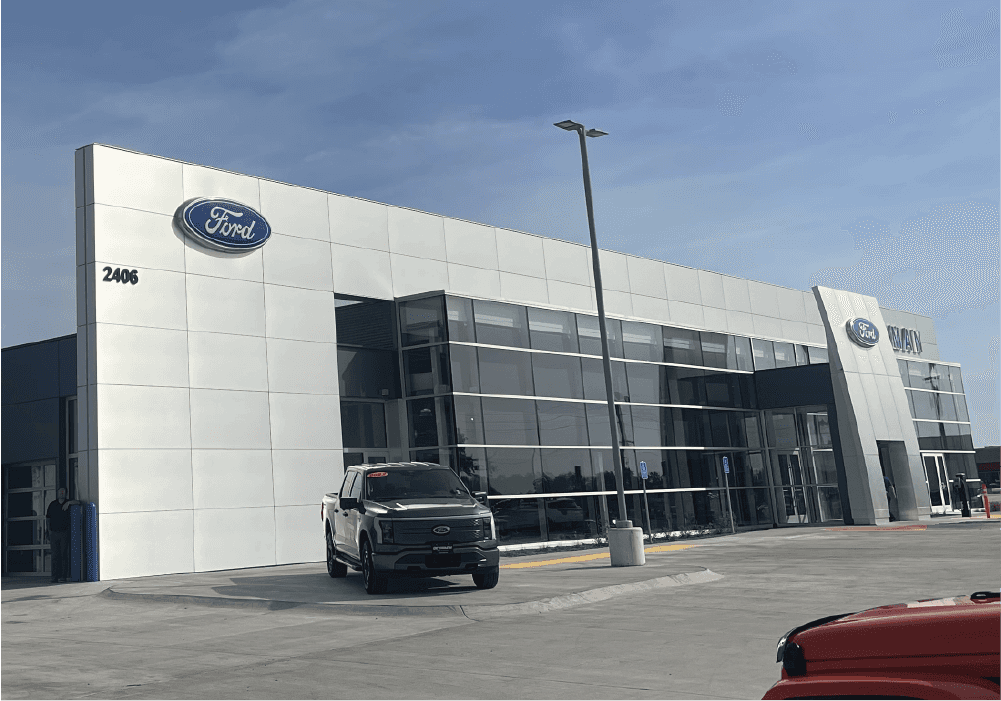 Outside of Ford Dealership, 2 New Ford Vehicles parked on the sidewalk. 