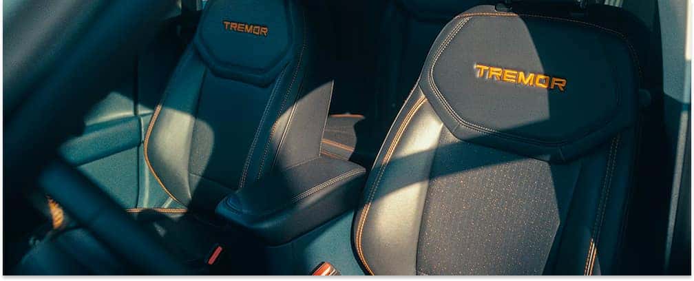 Black front seats with orange Tremor stitching inside a 2026 Ford Maverick.