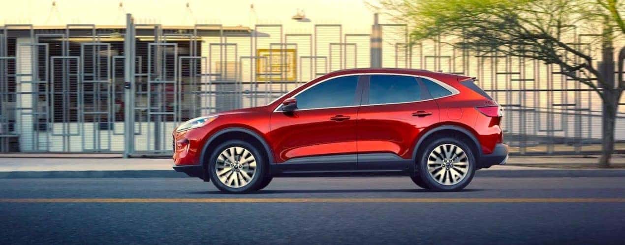 A red 2021 Ford Escape is shown from the side while driving in front of a modern metal fence.