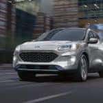 A silver 2020 Ford Escape Hybrid Titanium driving on a city street after visiting a Colorado Ford Escape dealer.