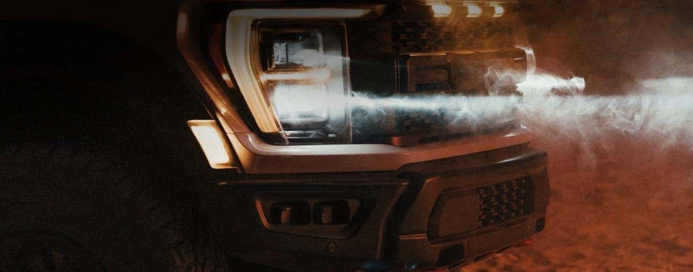 A close up shows the passenger side headlight on a black 2023 Ford F-150 Raptor R.