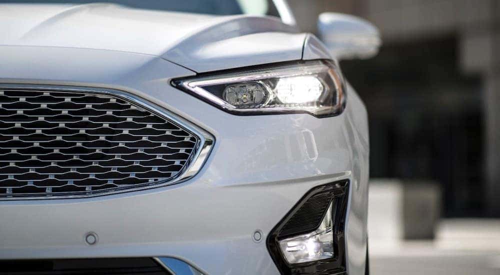 Close up of the driver side headlight and grille on a white 2020 Ford Fusion Hybrid.