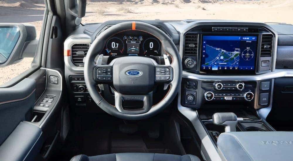 View from behind the steering wheel of a Ford F-150 Raptor, with digital displays across the dashboard