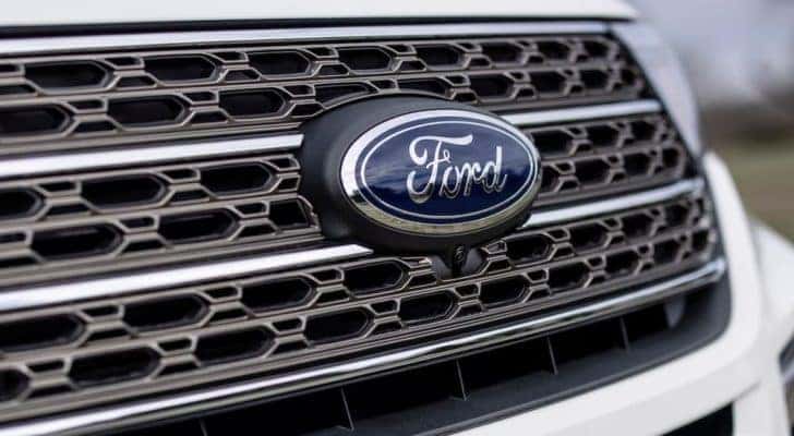 A closeup shows the Ford badging on the grille of a white 2021 Ford Explorer from a local Ford Explorer dealer.