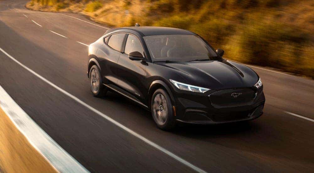 A black Ford Mustang Mach-e races down a sunny highway near Canon City, CO