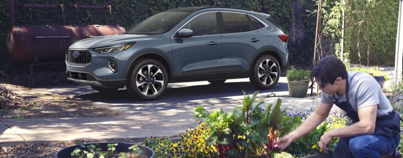 A person is shown tending to a garden next to a grey 2023 Ford Escape.