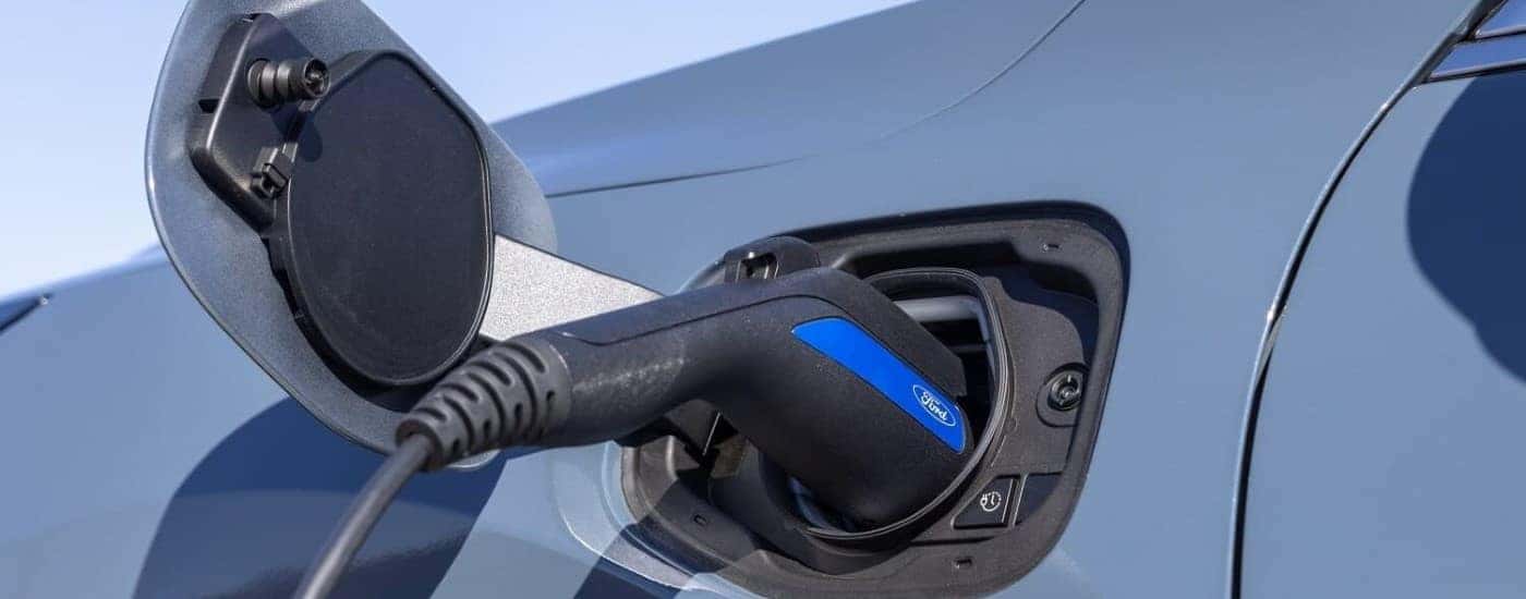A close up shows a blue 2023 Ford Escape charging.