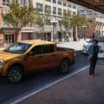 A yellow 2022 Ford Maverick is parked on a city street after leaving a Colorado Ford Maverick dealer.