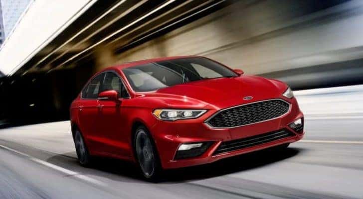 A red 2017 Ford Fusion is driving in a city underpass after leaving a Pueblo used car dealer.