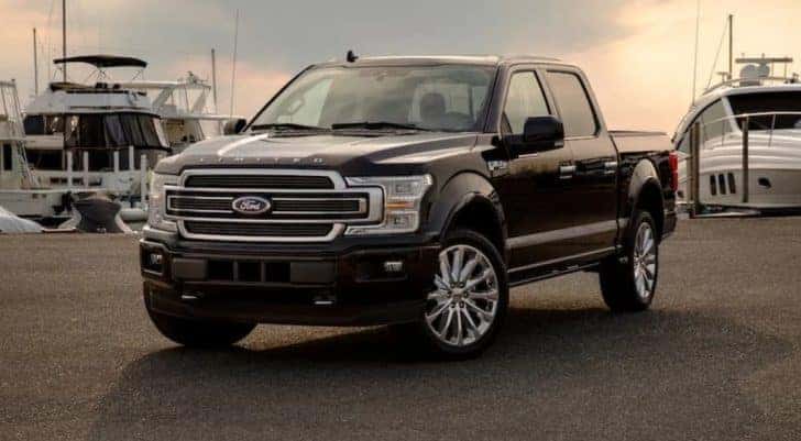 A black 2019 Ford F-150 Limited is parked in front of boats at a marina.