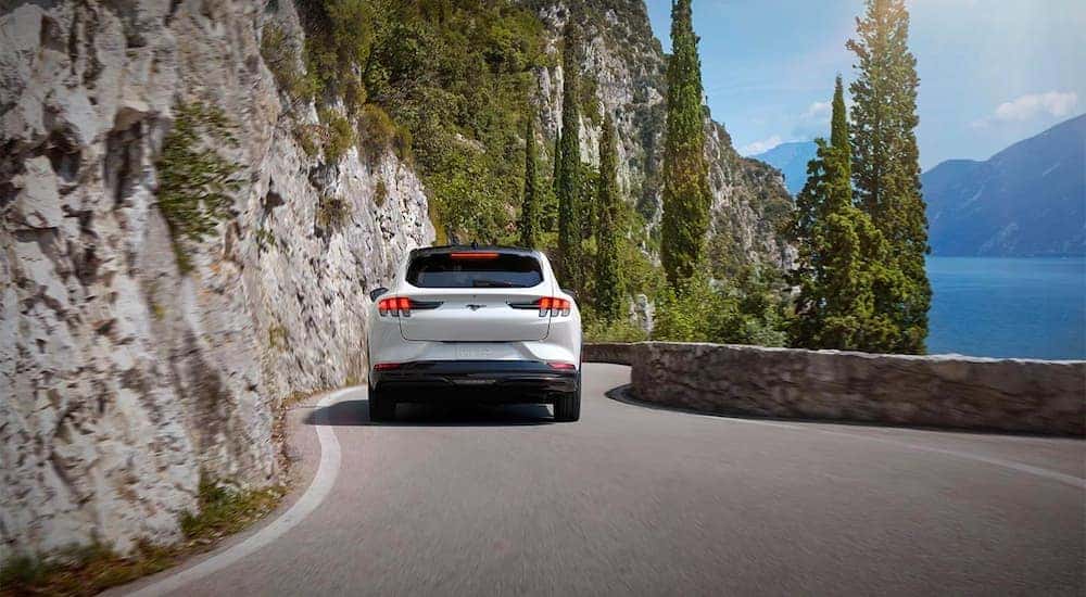 A white 2021 Ford Mach-E is shown from the rear driving away from a Colorado Ford Mach-E dealer.