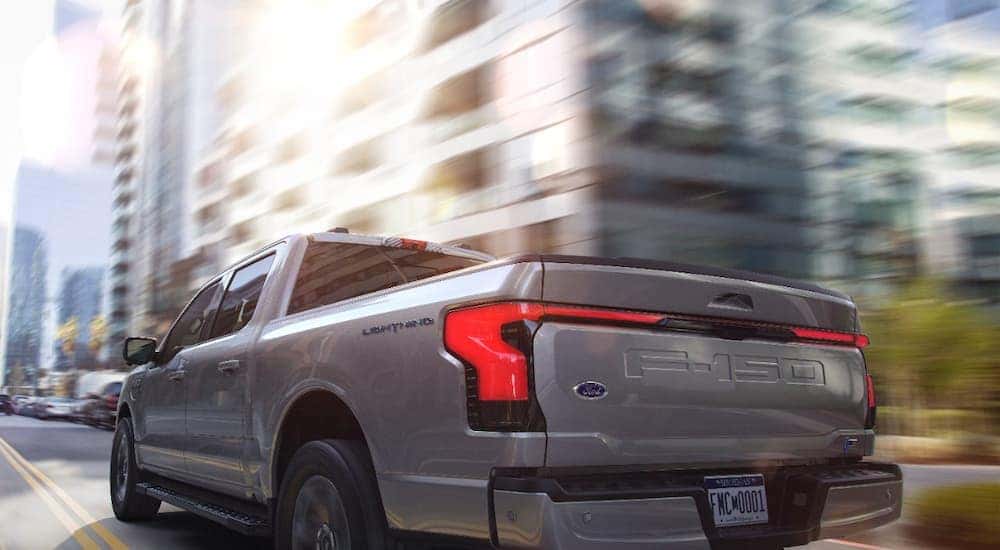 A grey 2022 Ford F-150 Lightning drives down a city street after leaving a Pueblo Ford F-150 dealer.
