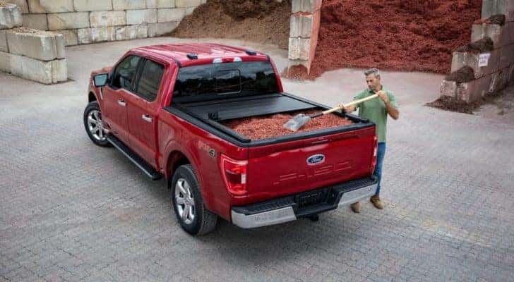 A red 2021 Ford F-150 is shown parked at a fill yard as it is being used to haul mulch.