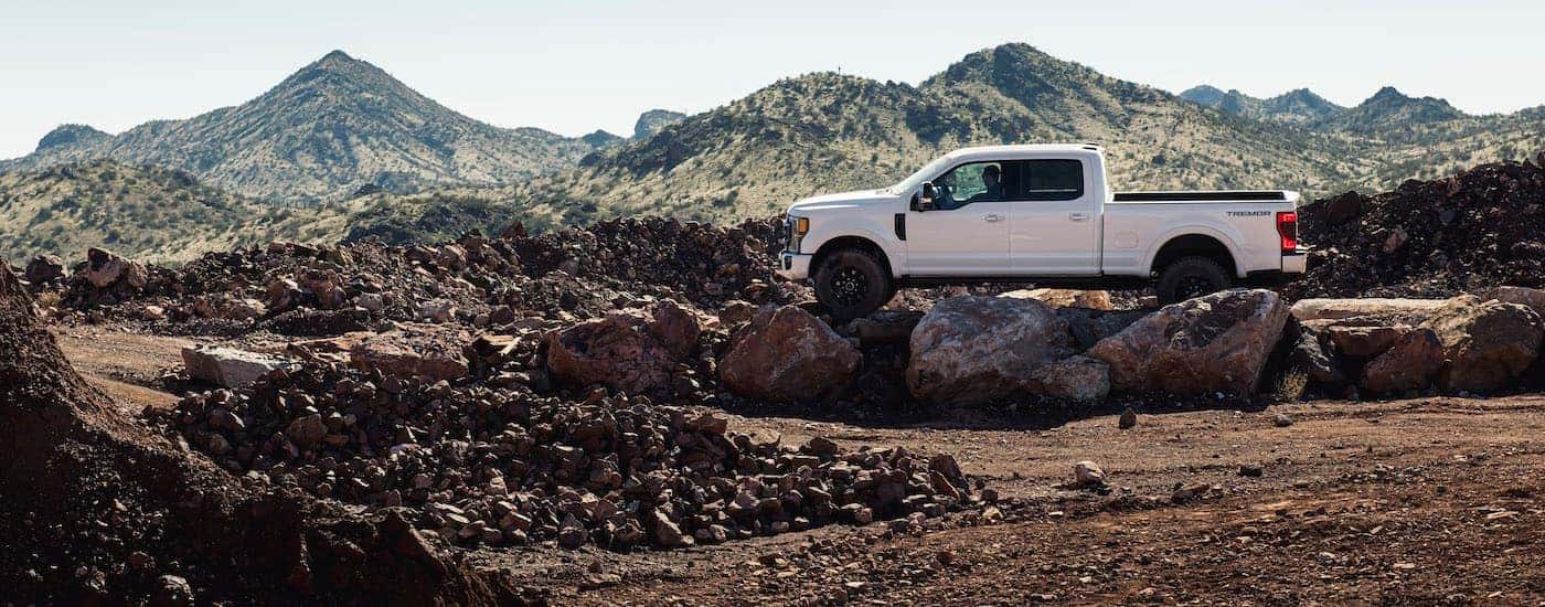 A white 2020 Ford F-250 Super Duty Tremor Sport is shown from the side parked on a rocky path.