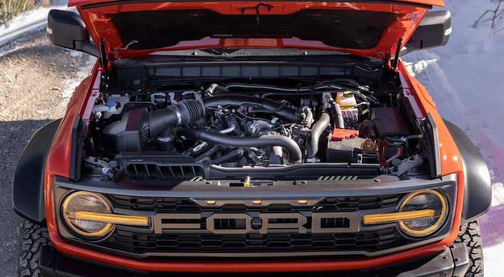An orange 2022 Ford Bronco Raptor is shown with the hood open.