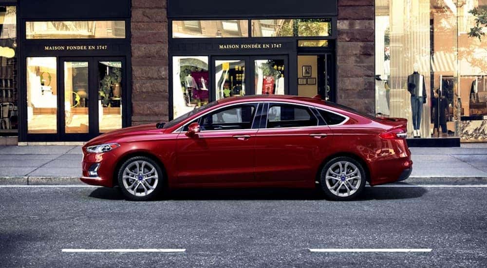 A red 2020 Ford Fusion is shown from the side parked on a city street.