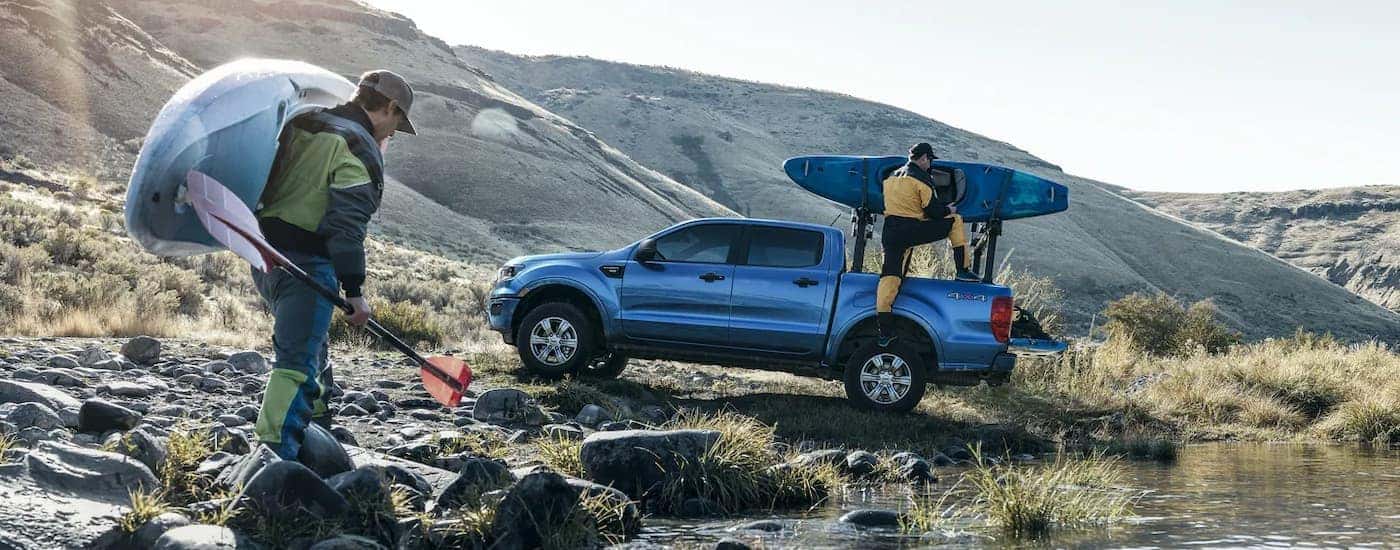 A blue 2022 Ford Ranger XLT is shown from the side near people carrying kayaks.