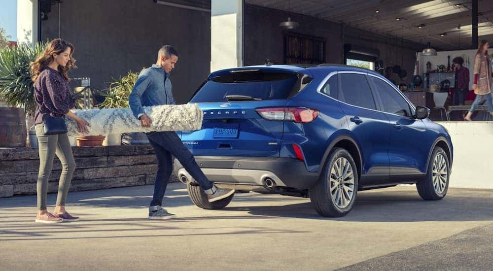 A blue 2022 Ford Escape is shown from the rear while the owner opens the hands free hatch.