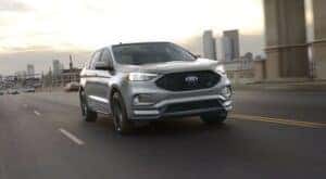 A grey 2023 Ford Edge ST is shown driving on an open road.