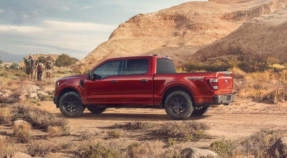 A red 2023 Ford F-150 Rattler is shown from the side while parked off-road after leaving a Ford F-150 dealer near Florence, CO.
