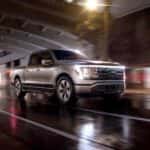 A silver 2023 Ford F-150 Lightning is shown from the front at an angle after leaving a dealer that has a Ford F-150 for sale.