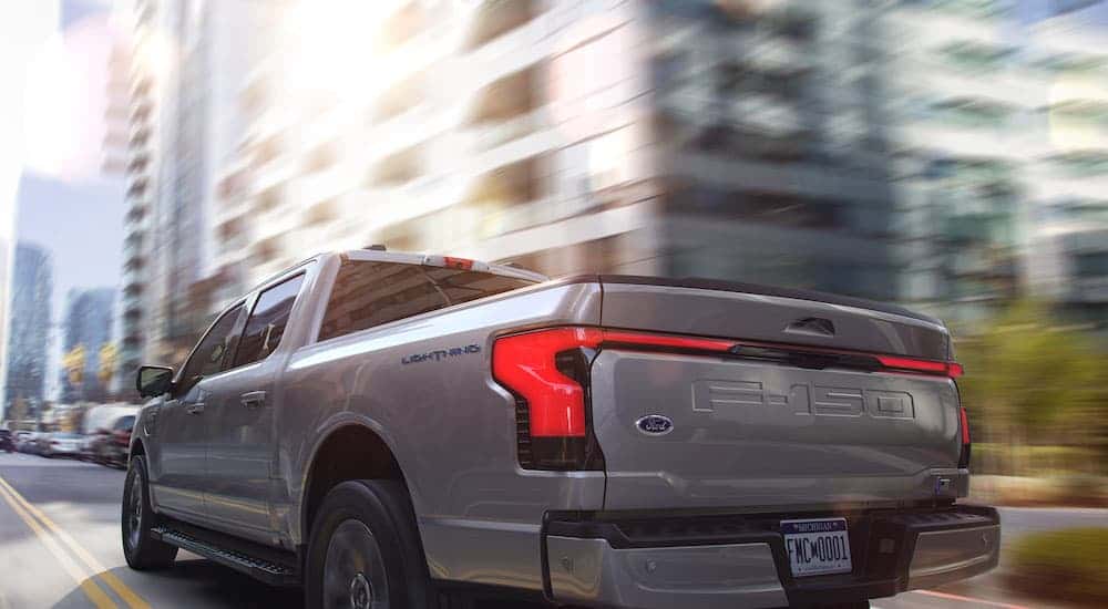 A silver 2023 Ford F-150 Lightning is shown from a rear angle.