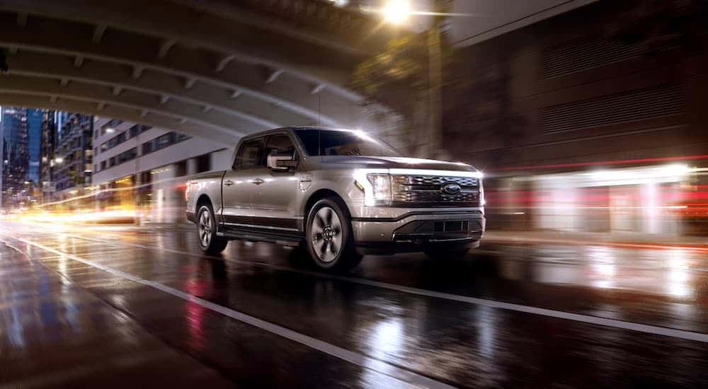 A silver 2023 Ford F-150 Lightning is shown from the front at an angle after leaving a dealer that has a Ford F-150 for sale.