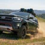 A green 2023 Ford Expedition Timberline is shown kicking up dust after looking at a Ford Expedition for sale.