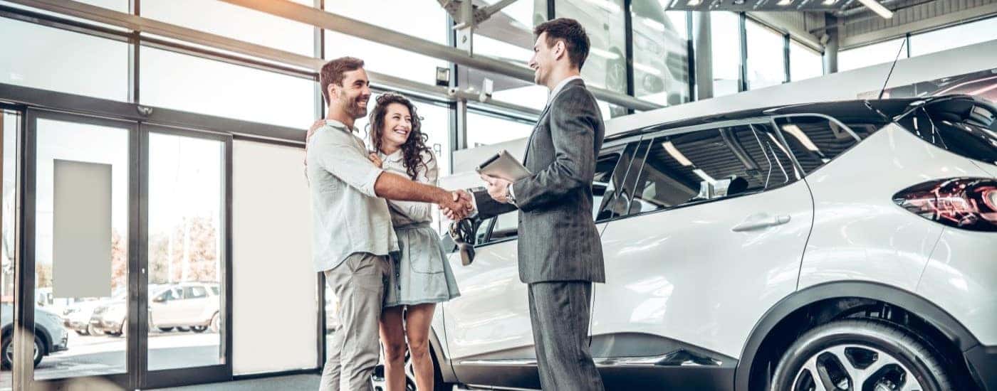 People are shown shaking hands at a used car buying center.