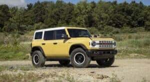 A yellow 2023 Ford Bronco Heritage Limited is shown parked off-road.