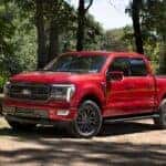 A red 2024 Ford F-150 Lariat is shown from the front at an angle.