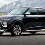 A black 2021 Kia Soul is shown driving from a dealer with used SUVs for sale.