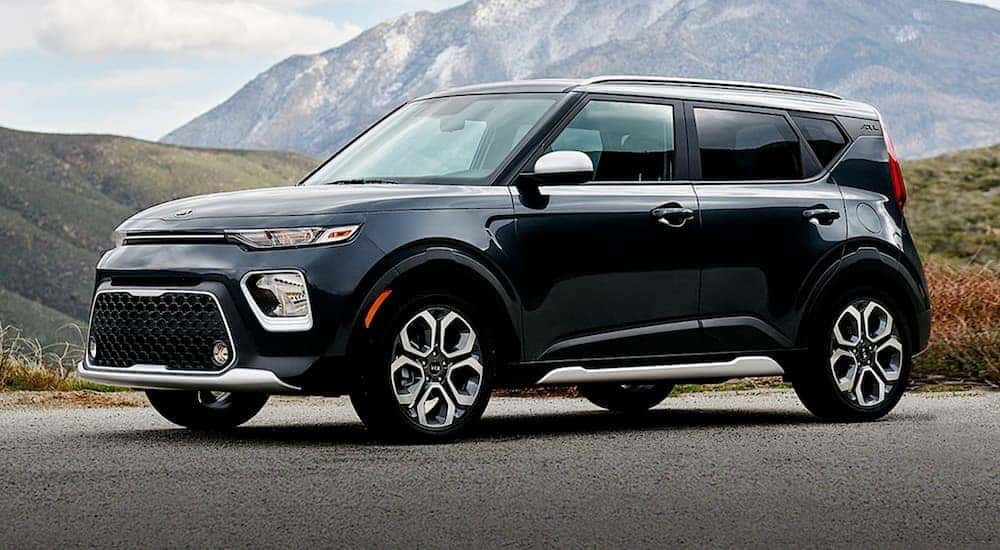 A black 2021 Kia Soul is shown driving from a dealer with used SUVs for sale.
