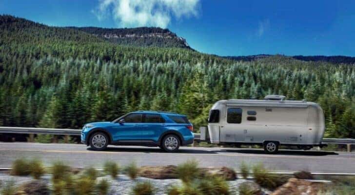 One of many popular used SUVs for sale, a blue 2023 Ford Explorer, is shown towing a trailer.