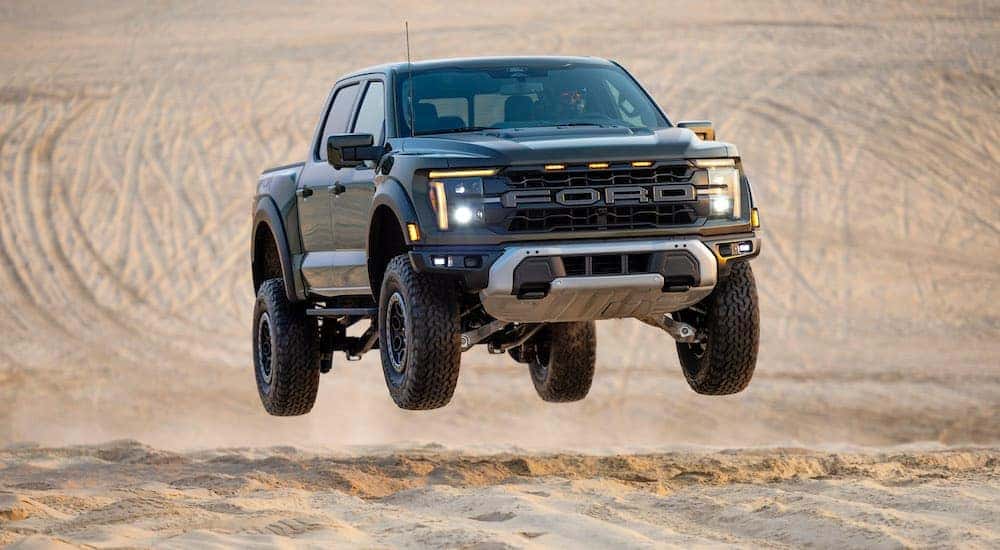 A green 2024 Ford F-150 Raptor is shown driving off-road after visiting a dealer with a Ford F-150 for sale near Pueblo West.