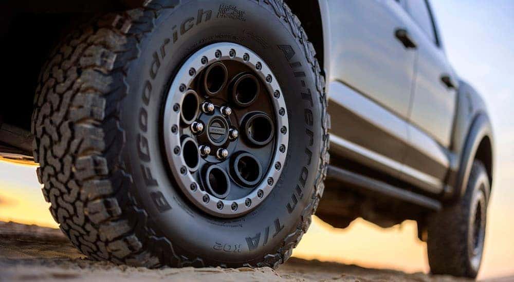 A close-up of a front wheel on a green 2024 Ford F-150 Raptor is shown.