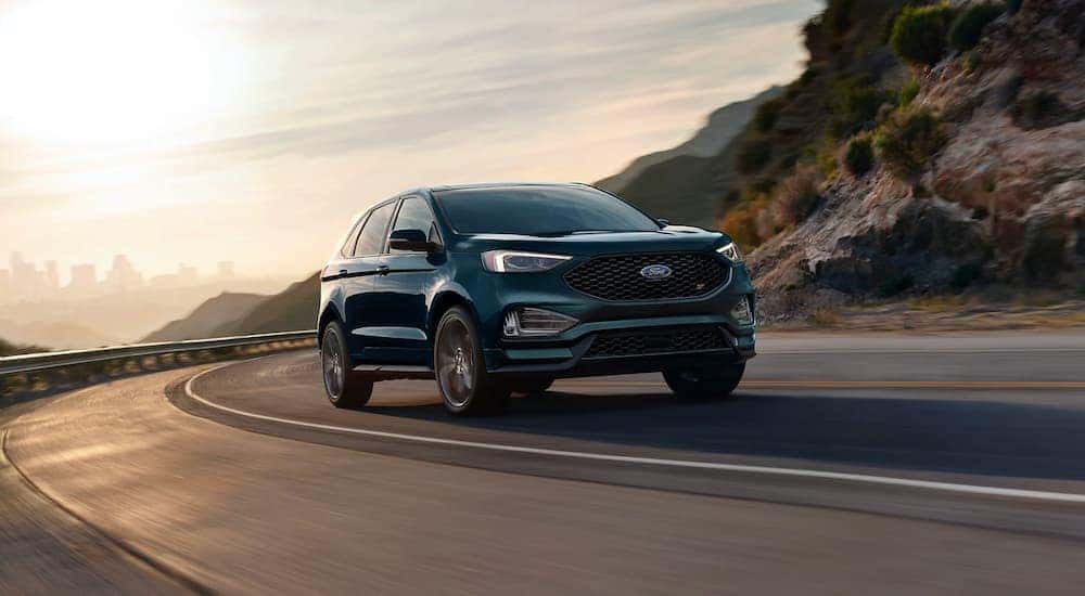 A teal 2024 Ford Edge ST driving on a mountain highway.