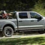 A gray 2024 Ford F-150 is shown driving uphill.