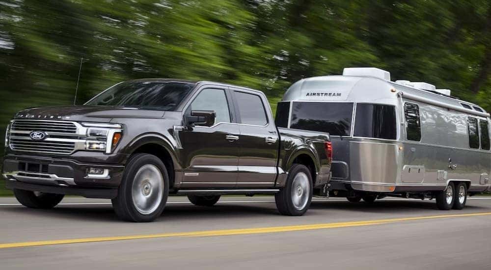 A black 2024 Ford F-150 Platinum is shown towing a trailer after visiting a Ford F-150 for sale near Colorado City.