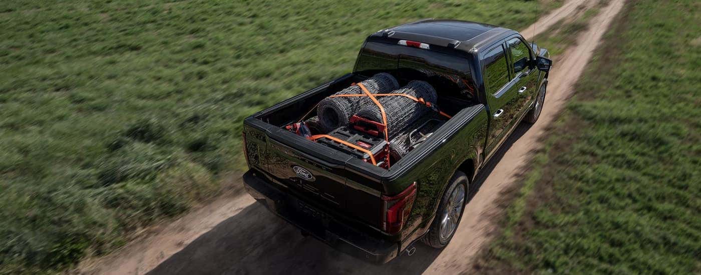 Overhead view of a black 2025 Ford F-150 Platinum driving with fencing materials in the bed.