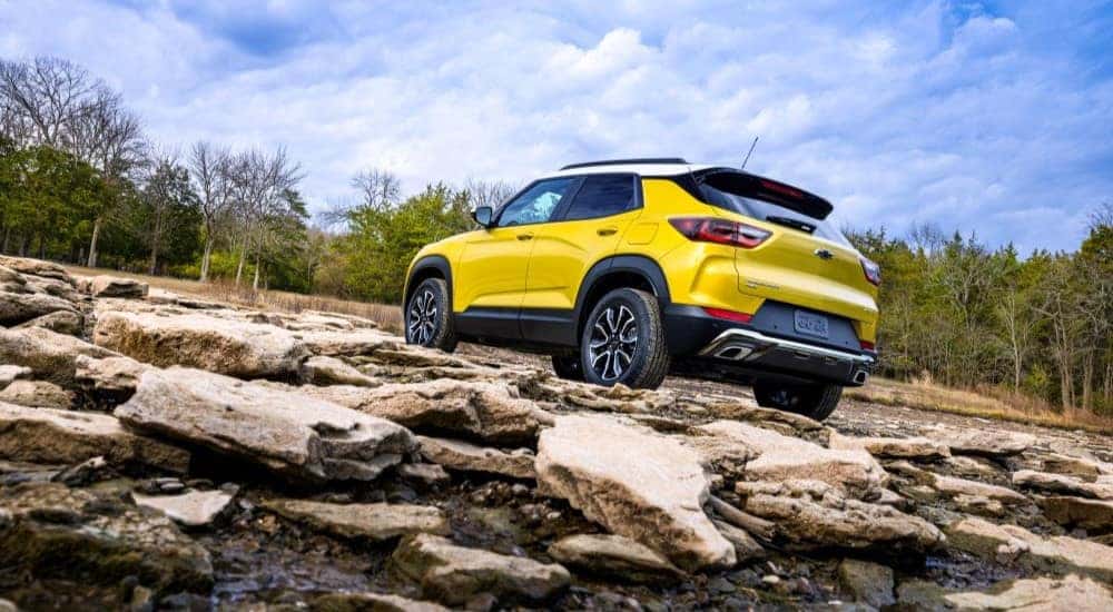 A yellow 2024 Chevy Trailblazer ACTIV driving up a rocky hill.