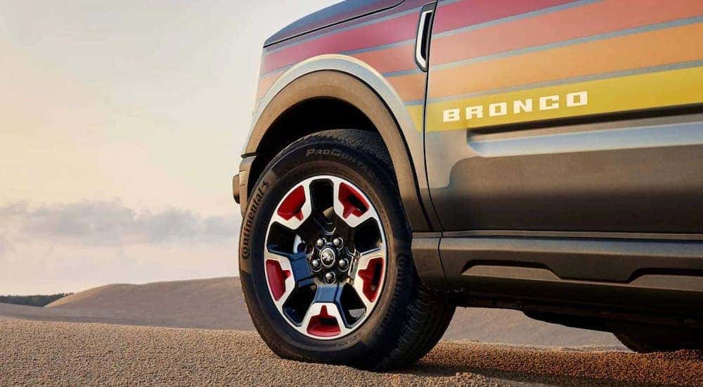 A close-up on the wheel of a multicolored 2024 Ford Bronco Sport Free Wheeling parked in a desert.