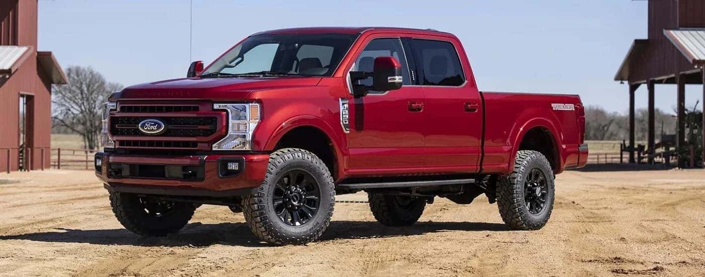 A red 2022 Ford F-250 Lariat is shown from the side after leaving a dealer that has used trucks for sale.