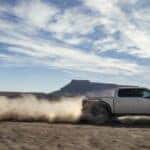A white 2025 Ford F-150 Tremor is shown driving off-road after viewing a Ford F-150 for sale near Westcliffe.