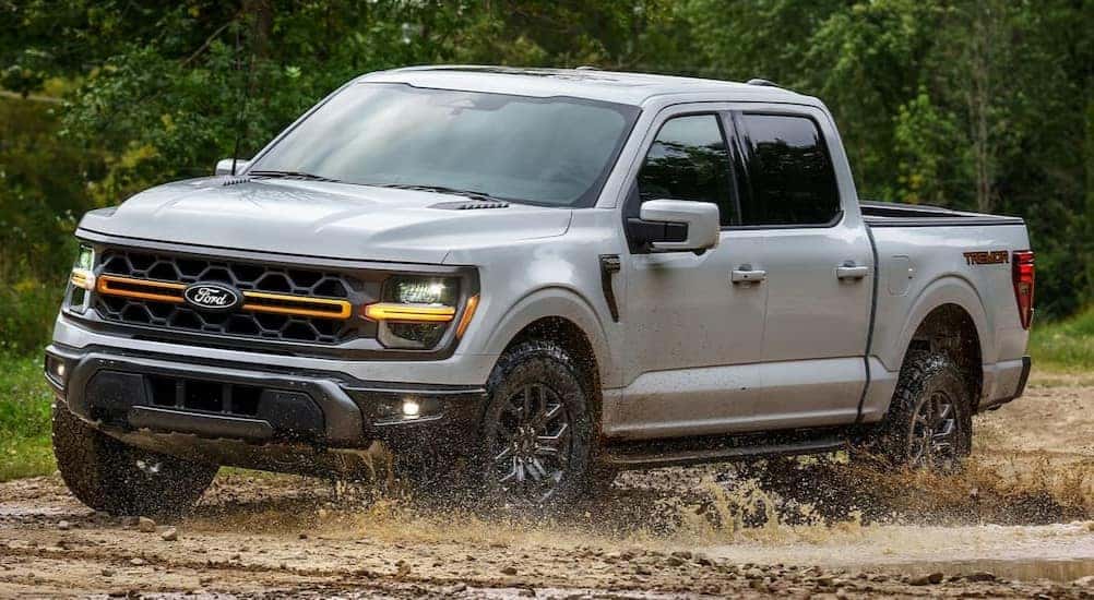 A white 2025 Ford F-150 Tremor is shown driving on mud.